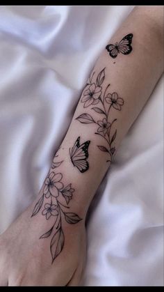 a woman's arm with flowers and butterflies on it, while she is laying in bed