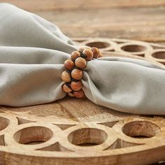 a napkin with some beads on it sitting on top of a wooden table next to a piece of wood