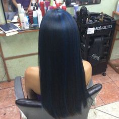 the back of a woman's head with blue hair sitting in a salon chair