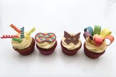 three cupcakes are decorated with colorful decorations