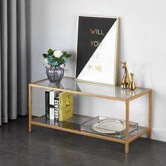 a glass table with some books and vases on it next to a wall mounted art piece