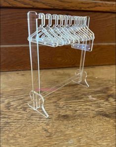 a clear plastic rack with five hangers on it's sides, sitting on a wooden surface