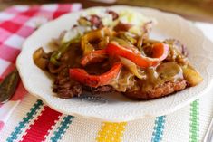 a white plate topped with meat covered in gravy and veggies next to a fork