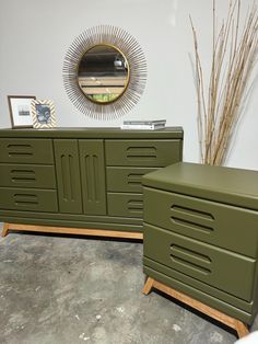 two green dressers sitting next to each other on top of a cement floor in front of a mirror