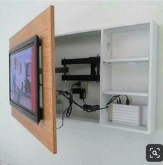 a tv mounted to the side of a white wall next to a wooden framed object