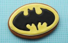 a decorated cookie with the symbol of batman on it's side, sitting on a blue surface