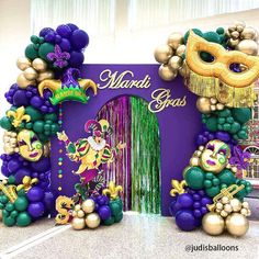 mardi gras decorations are displayed in front of a purple backdrop with gold and green balloons