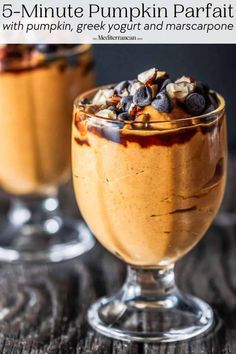 two glasses filled with dessert sitting on top of a table