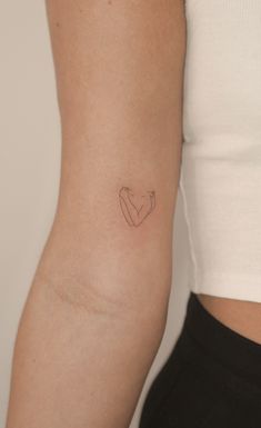 a woman's arm with a small heart tattoo on the left side of her arm