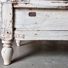 an old white wooden table with peeling paint on the top and bottom drawers, sitting in a room