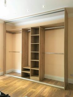 an empty room with wooden floors and open closets on the wall, in front of a hard wood floor