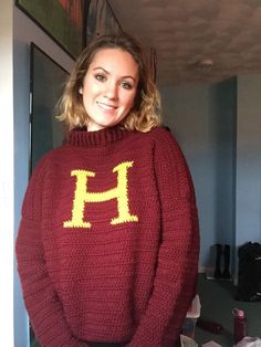 a woman wearing a sweater with the letter h on it