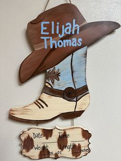 a cowboy hat hanging on the wall next to a sign that says, eljah thomas