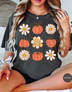 Embrace the nostalgic vibes of autumn with our Retro Bloom & Harvest Tee! This enchanting design features a delightful blend of cheerful daisies and charming pumpkins, capturing the essence of fall in a retro-inspired style. Perfect for pumpkin patch outings, cozy bonfires, or just celebrating the beauty of the season, this tee brings a touch of vintage charm to your autumn wardrobe. Soft, comfortable, and effortlessly stylish, it's the perfect piece to welcome the fall season with open arms. Get ready to bloom and harvest in style! Tennessee Outfits, Shift Pattern, Glamour Outfit, Black Pumpkin, Amazing Ideas, Floral Print Shorts, Vintage Western, Soft Tops, Floral Style