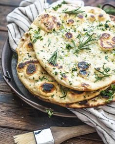 three flat bread pizzas are on a plate with a cloth and knife next to it