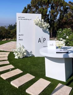 an outdoor ceremony setup with white flowers on the grass and steps leading up to it