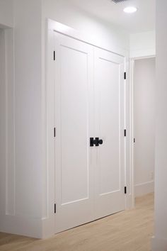 an empty room with white walls and black handles on the doors, wood flooring