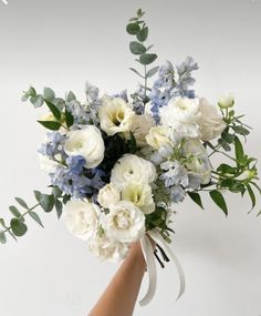 a hand holding a bouquet of white and blue flowers