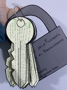 a hand holding a key to a door with several keys attached to it and some paper tags hanging from the front