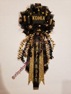 a black and gold happy birthday decoration hanging from a wall with the words keora on it