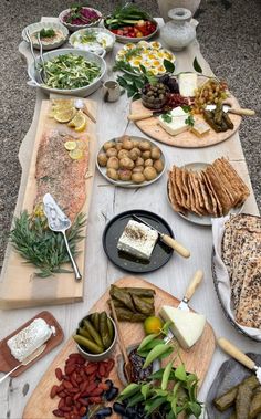 a table topped with lots of different types of foods and cheeses on top of wooden cutting boards