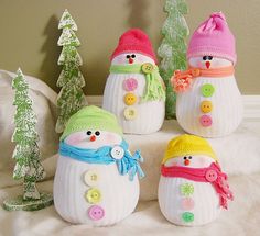 four snowmen with hats and scarves are sitting on a bed next to christmas trees