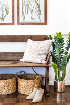 a wooden bench sitting next to two planters and baskets on top of a hard wood floor