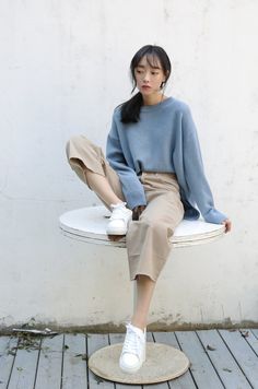 a young woman sitting on top of a white toilet seat next to a wooden floor