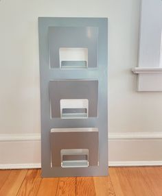 a metal object sitting on top of a hard wood floor next to a white wall