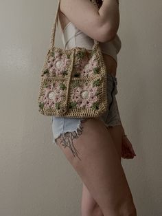 a woman is holding a crocheted purse in her right hand and posing for the camera