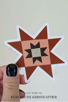 a hand holding up a sticker with a star design on it