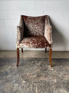 a brown and white chair sitting on top of a cement floor next to a brick wall