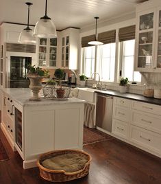 a large kitchen with white cabinets and wooden flooring, along with a basket on the island