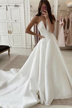 a woman taking a selfie in front of a mirror wearing a white wedding dress