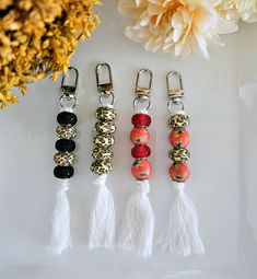 four keychains with tassels and beads on them next to a flower