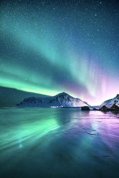 the aurora bore is shining brightly in the night sky over water and snow covered mountains