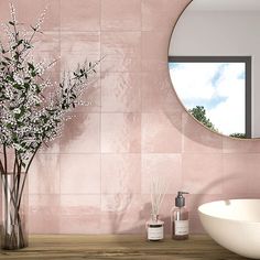 a bathroom with pink tiles and a round mirror on the wall next to a sink