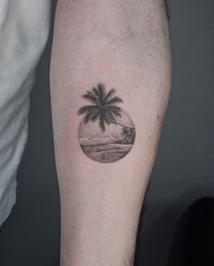 a man's arm with a small palm tree tattoo on it