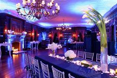 a dining room set up for a formal function with candles and flowers on the table