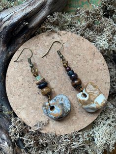 I found these beautiful hag stones with grey, mustard and white patterning out on a long walk in my homeland of the UK. I decided to pair them with a variety of earthy stacked wooden and glass beads in rustic browns, blacks and a pop of green. The hag stones are a witchy nod to the inherent magick of the natural landscape and the upcycled vintage beads add a funky boho touch. Surprisingly, they are not too heavy. Pair with this primitive Bone and Hag Stone Necklace for the ultimate witchy protec Hag Stone Jewelry, Earthy Jewelry With Matching Earrings For Everyday, Earthy Handmade Earrings For Everyday Wear, Handmade Earthy Drop Earrings, Earthy Handmade Drop Earrings, Earthy Drop Earrings With Natural Stones, Earthy Natural Stone Drop Earrings, Hag Stone Necklace, Witchy Boho