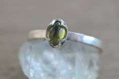 This dainty peridot ring will be made to order for you within 10 business days. It will be packaged in a little gift box along with a polishing cloth. The gemstone is a 6mm x 4mm oval peridot cabochon, a natural green stone. We've set it in a unique crown style bezel cup. The ring band is approximately 2mm wide with a smooth finish. It's entirely sterling silver, cast in recycled and reclaimed materials. We can personalise the inside of this simple peridot ring for you with engraving inside the Silver Peridot Ring, Ring Bezel, Sterling Silver Jewellery, Peridot Ring, Green Crystal, Oval Stone, Green Crystals, Ring Band, Green Stone