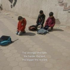 three boys sitting on the ground with their backpacks in front of them, one boy is reading