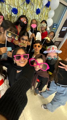 a group of people wearing pink sunglasses and some have fake masks on their faces as they pose for a photo