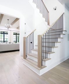 a white staircase with black handrails and wood flooring in a large home