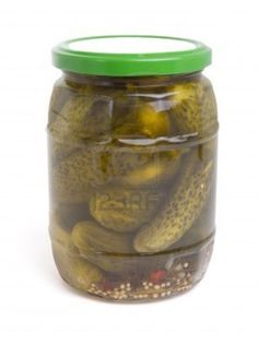 pickled cucumbers and other vegetables in a glass jar with green lid on white background