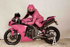 a man in pink riding on the back of a motorcycle next to another person wearing a helmet