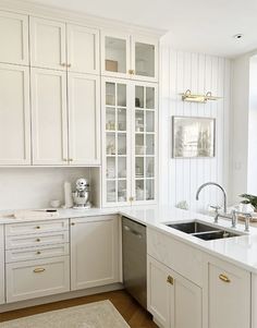 a kitchen with white cabinets and gold handles on the sink, dishwasher and oven