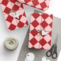 three wrapped presents are sitting on a table next to scissors and twine with heart tags