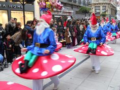 several people dressed as gnomes are walking down the street in front of a crowd