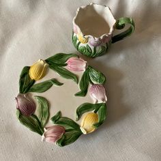 two ceramic dishes sitting on top of a white cloth covered tablecloth next to each other